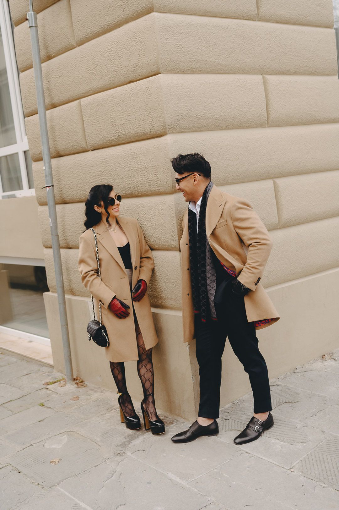 Doug and Natalie in camel overcoats against a Florence wall.
